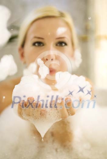 Woman blowing the foam in the bath