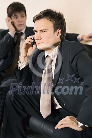 Two businessmen talking to a phone