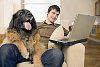 Man sitting on the couch with a dog and laptop