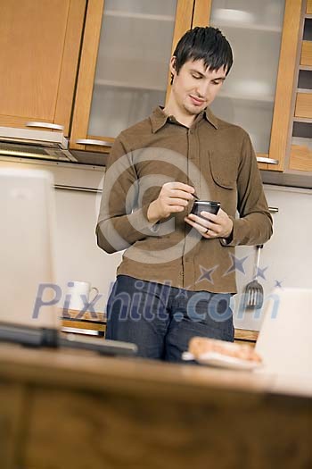 Man standing in the kitchen looking at his planner
