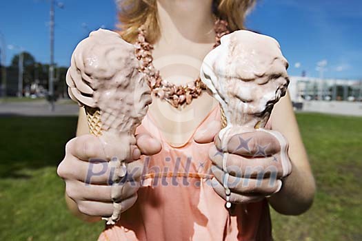 Woman offering two icecreams that have started to melt Woman offering two icecreams that have started to melt