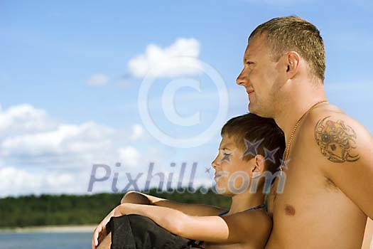 Man and a boy sitting on the beach