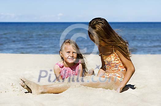 Two girls palying with sand on the beach