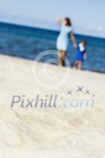 Woman and child walking on the sand