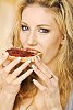 Woman taking a bite of white bread with jam on it