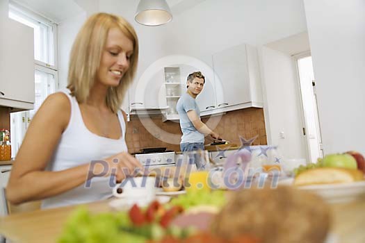 Woman and man in the kitchen prepearing and having breakfast