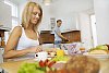 Woman and man prepearing and having breakfast