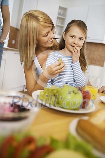 Woman and girl having grapes on the kitchen table