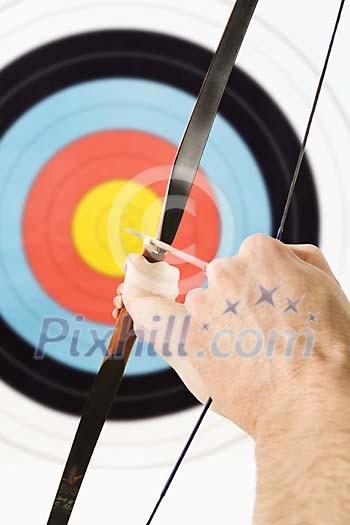 Mans hand holding a bow and aiming the target