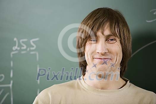 Man smiling in front of blackboard