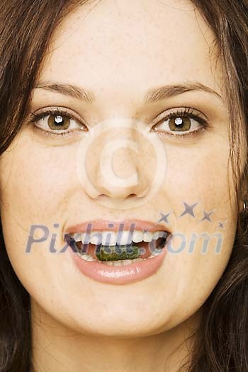 Woman holding a pill between her teeth