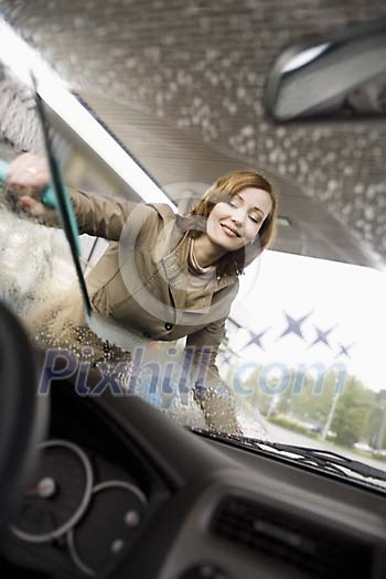 Woman cleaning her car windshield