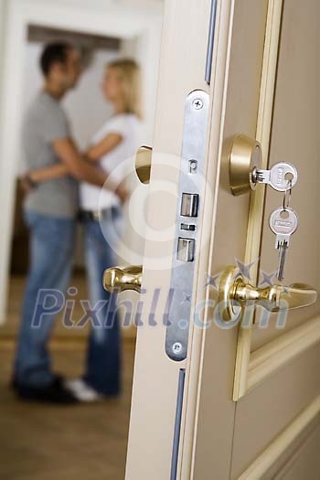 Couple standing behind an open door