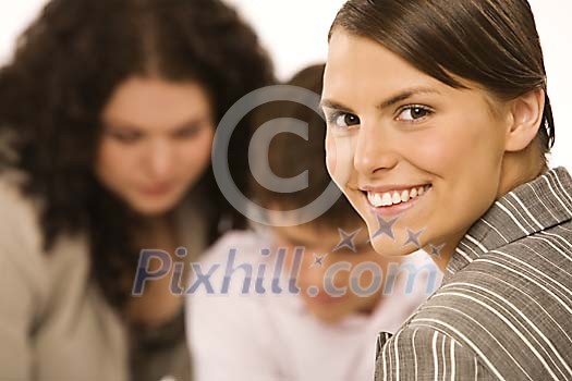 Businesswoman smiling up front and to other people reading at the back