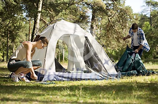 Couple in the woods, putting up the tent