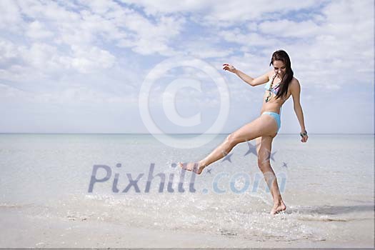 Woman splashing water with her foot at the beach