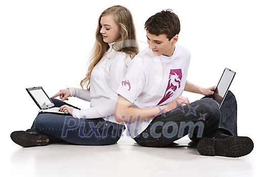 Couple of teenagers sitting on the floor with laptops
