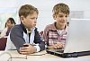 Two schoolboys with a laptop in the classroom