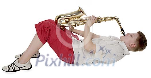 Isolated boy laying down, playing saxophone