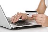 Female hands holding a credit card and touching a laptop