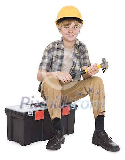 Isolated boy dressed as a carpenter sitting on the toolbox