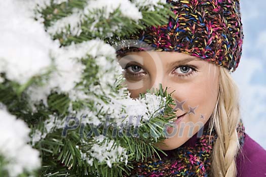 Woman peeking behind snowy branches