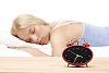 Blurred woman sleeping with alarm clock on display