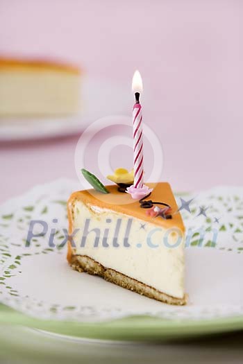 Piece of cake with a lit candle on the plate