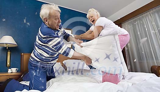 Senior couple having a pillow fight on the bed