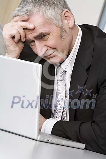 Older businessman looking tired at his desk