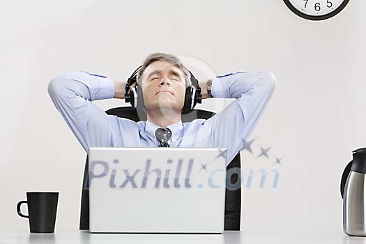 Businessman listening to music at his desk Businessman listening to music at his desk