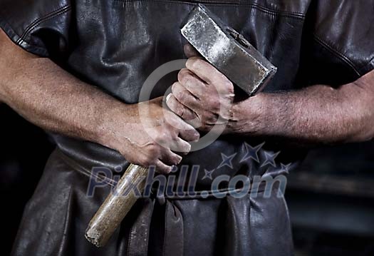 Male hands holding a blacksmiths hammer Male hands holding a blacksmiths hammer