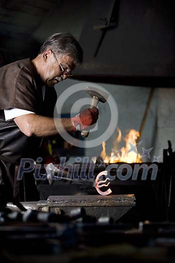 Male blacksmith hitting hot iron