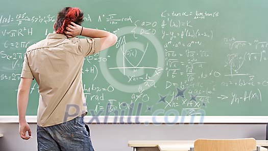 Male teenager thinking in front of the blackboard