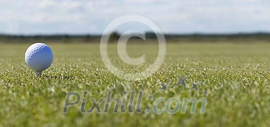 Golf ball on a tee on a green field