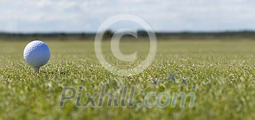 Golf ball on a tee on a green field Golf ball on a tee on a green field