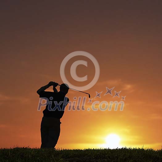 Male golfer at the golfcource on the sunset