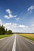 Empty road surrounded by forest and fields