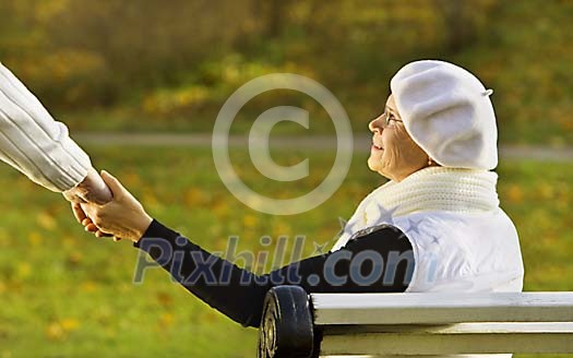 Senior woman in park holding her husbands hand