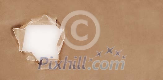 Ripped hole in brown paperboard Ripped hole in brown paperboard