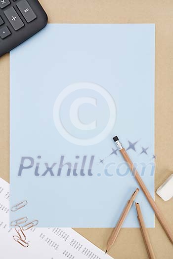 Empty blue paper surrounded by pencils, paper clips and calculator