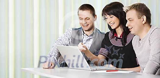 Three young people behind one laptop Three young people behind one laptop