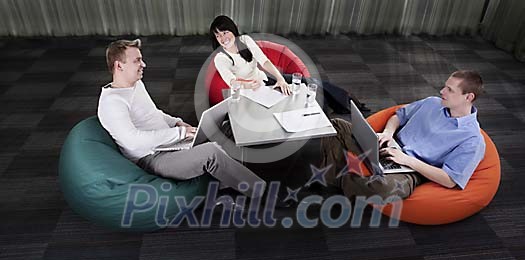 Young people having a meeting while sitting in beanbag chairs
