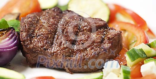 Grilled fillet of beef on plate surrounded by vegetables