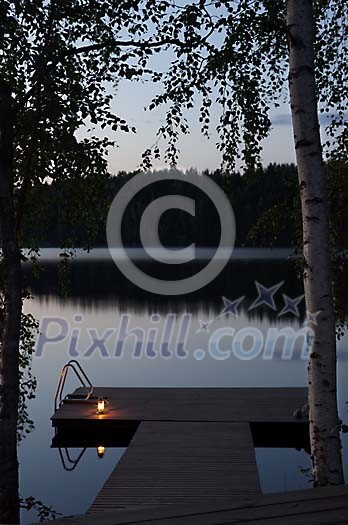 Evening dusk and lighted pier by a calm lake