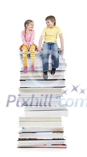 Girl and a boy sitting on a high stack of books
