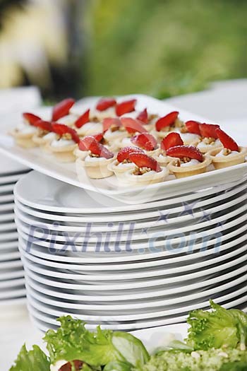Strawberry snacks on top of a pile of plates Strawberry snacks on top of a pile of plates