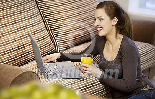 Woman sitting by the couch with laptop
