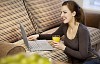 Woman sitting by the couch with laptop