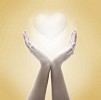 Hands with shining heart on a beige background